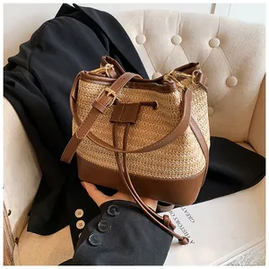 Detail of woven straw bucket bag with dark brown leather trim and drawstring closure