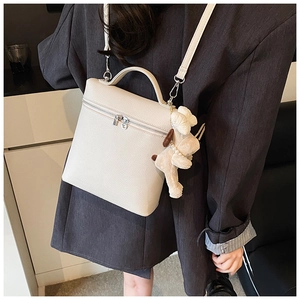 Close-up of cream lychee texture leather bucket bag with cute plush puppy charm
