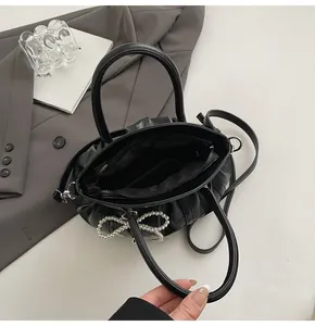 Interior detail of a black pleated motorcycle bag with zip pocket and pearl bow accents