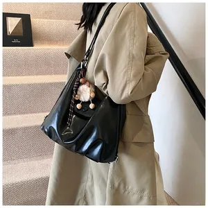 Side view of large black slouchy tote bag with a plush lamb charm on model