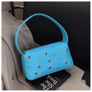 Detailed shot of bright blue leather bag with silver eyelets on a fashion book background