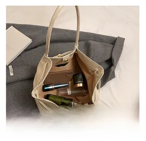 Top view of large cream tote bag interior showing spacious storage with cosmetics and phone