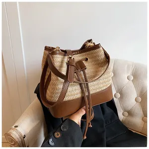 Close-up of straw bucket bag with brown leather trim and drawstring closure detail