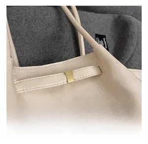 Detail of the golden rectangular metal buckle on a beige pleated leather tote bag