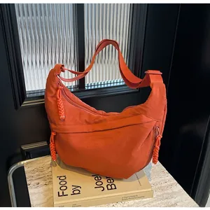 Detail of orange hobo bag with woven zipper pull on textured nylon fabric