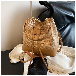 Detail of hand-woven straw bucket bag with faux leather trim and golden chain strap