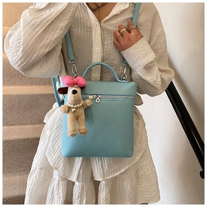 Close-up of light blue pebble leather handbag with cute plush puppy charm accessory