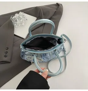 Macro view of metallic light blue handbag showing interior zipper pocket and pearl bow