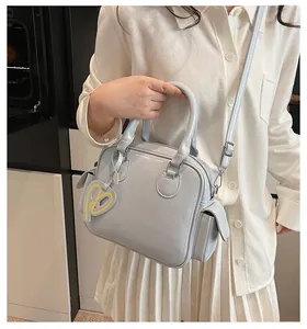 Detailed view of light blue tote bag with heart pendant and adjustable shoulder strap