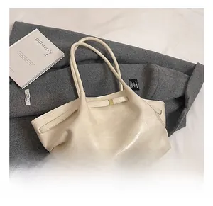 Detail of cream-colored pleated tote bag with glossy finish and metal buckle