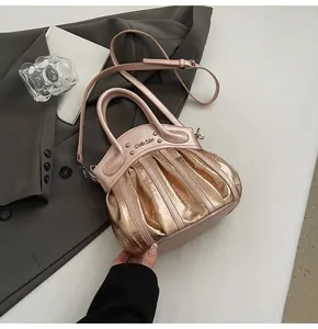 Detailed close-up of rose gold pleated motorcycle bag with silver rivets and sleek handle