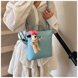 Detail of light blue lychee pattern crossbody bag with a cute plush dog charm