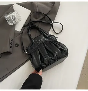 Detail of black pleated biker bag with matte leather finish and metal letter logo accents