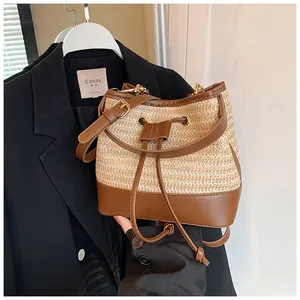 Close-up of woven straw bucket bag with brown leather drawstring and adjustable strap