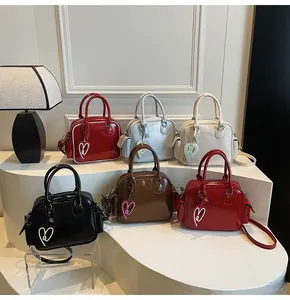 Detail of multi-color patent leather bowling bags featuring heart-shaped charms and side pockets
