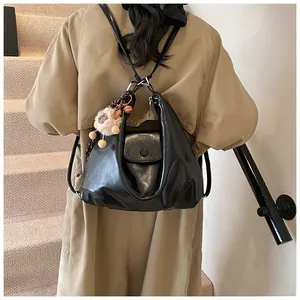 Detail of black PU leather backpack with folding design, soft pleats and cute plush charm