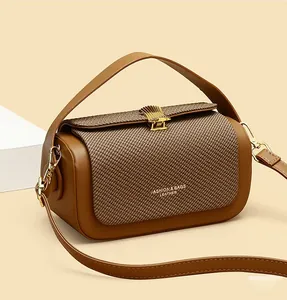 Detail of caramel box bag showing textured fabric flap and gold metallic clasp