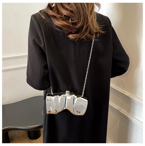 Détail d'un sac à bandoulière argenté brillant ondulé avec une fine chaîne en métal
