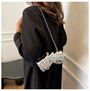 Détail du sac fer à cheval argenté avec chaîne métallique sur un blazer noir