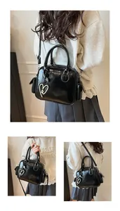 Detail view of glossy black tote bag with heart charm and adjustable shoulder strap