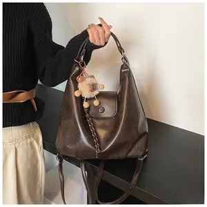 Close-up of vintage brown leather backpack with cute bear charm and soft polished texture