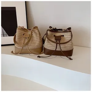Detail of woven straw bucket bags with leather trim and drawstring closure in two colors