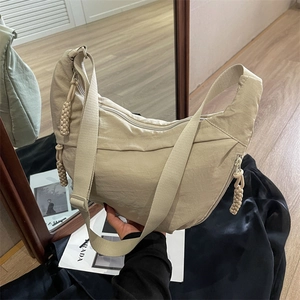 Chic beige nylon dumpling bag with adjustable strap and decorative zipper for daily commute