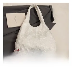 Detail of white tote bag featuring 3D floral embroidery on lightweight mesh fabric