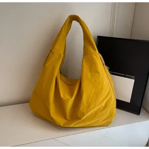 Detail van heldergele geplooide nylon hobo-tas met brede schouderband en trekkoord