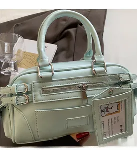 Detailed close-up of a mint green Boston bag with dual handles and dog charm accessory