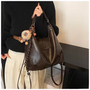 Detail of a large dark brown leather backpack with a plush lion charm on model