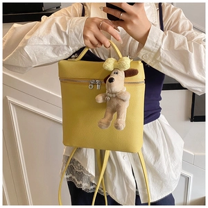 Detail of yellow pebbled leather backpack with a cute plush dog pendant charm