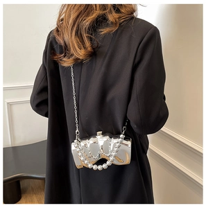 Détail du sac bandoulière argenté avec texture ondulée et poignée à grosses perles
