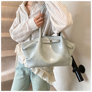 Side view of large silver patent leather tote bag with pleated detail and metal buckle