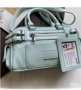 Detail of light blue crossbody bag featuring adjustable buckles and a cute bear card holder