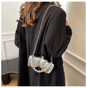 Détail d'un sac bandoulière miroir argenté avec poignée perle et chaîne sur costume noir