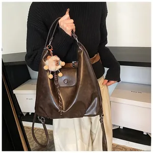 Macro shot of dark brown oil-wax leather shoulder bag with vintage lion plush pendant detail