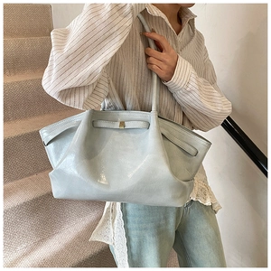 Detail of light blue pleated leather tote bag with elegant gold metal buckle accent
