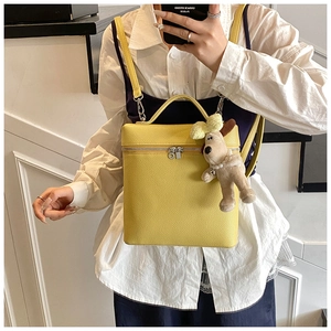 Detail of yellow pebbled leather backpack with cute dog plush charm and silver zippers