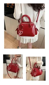 Detail of red glossy patent leather tote bag with white piping and heart charm accent