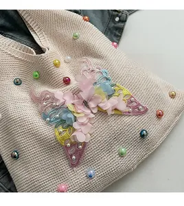 Detail of soft knit fabric with colorful bead accents and 3D fabric butterfly applique