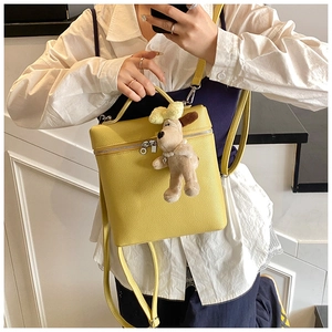 Detail of yellow pebble leather backpack with cute plush dog charm and metal zipper