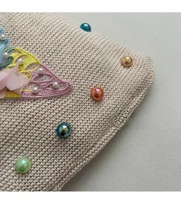 Close-up of beige woven bag with colorful beads and 3D floral embroidery detail