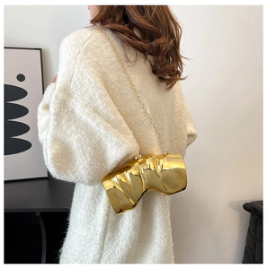 Pochette plissée irrégulière en métal doré avec fine chaîne portée par un modèle