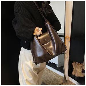 Detail of dark brown vintage faux leather tote bag with a cute plush sheep charm