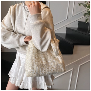 Close-up of white lace tote bag with delicate floral embroidery and spacious design