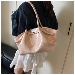 Detail of light pink pleated tote bag with golden buckle and sleek leather texture