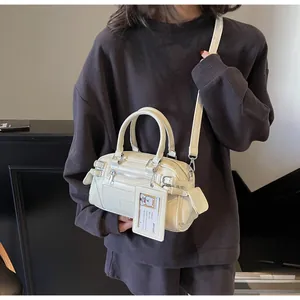 Close-up of cream leather Boston handbag with buckles, front zip pocket and top handles