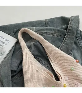 Close-up of pink knit shoulder bag with colorful beads on a casual denim background