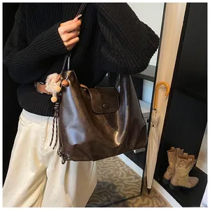 Detail of a vintage dark brown faux leather hobo tote bag with a soft plush charm